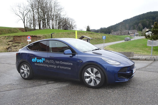 Tesla Model Y parked on a rural road, showcasing its hybrid technology and low CO2 emissions.