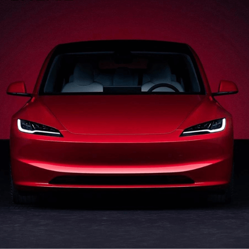 Front view of a red Tesla model showcasing sleek design and bright LED headlights.