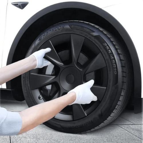 Person installing a black 19-inch wheel cover on a Tesla, showcasing modern design and quality craftsmanship.