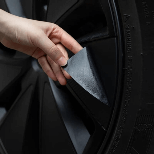 Person applying covering on a wheel of a Tesla Model 3 Highland for enhanced style and protection.