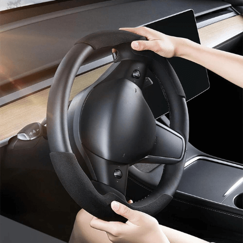 Couvre volant en suédine pour Tesla, offrant confort et style, vue des mains sur le volant pendant la conduite.