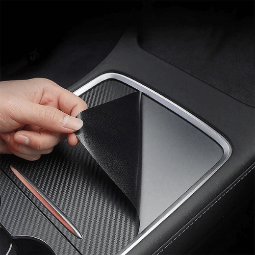 Hand removing a premium covering for the central console of a Tesla, showcasing stylish protection.