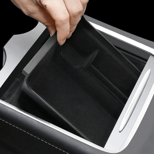 Main organiser being removed from a Tesla center console for optimized storage and organization.