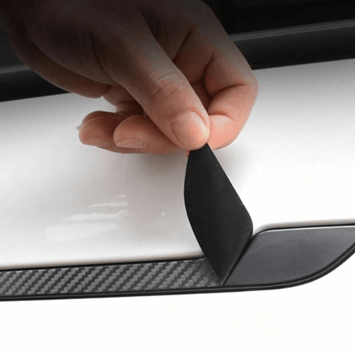 Person applying a door handle covering on a Tesla Model 3 or Y for enhanced protection and appearance.