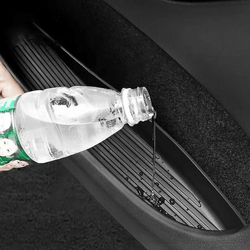 Person pouring water from a bottle into a door pocket of a Tesla Model Y showcasing its durability and design.