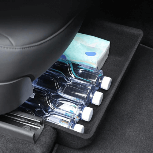 Bac de rangement sous siège avec bouteilles d'eau et mouchoirs, optimisant l'espace dans une Tesla Model Y.