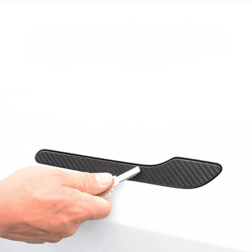 Person applying carbon fiber door handle wrap to Tesla Model 3 or Model Y for enhanced protection and style.