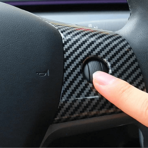 Close-up of a Tesla steering wheel cover with a finger adjusting the control, showcasing premium texture and finish.