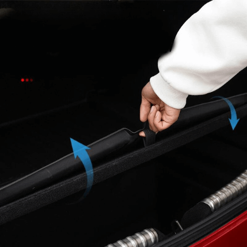 Person installing a Tesla Model 3 trunk sill protector to prevent scratches and wear.
