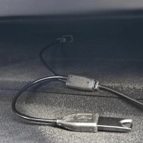 Câble USB connecté à un appareil dans un espace intérieur sombre.