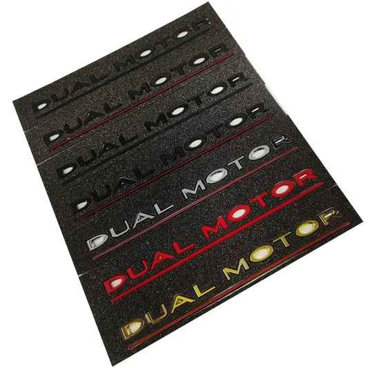Collection of elegant Dual Motor badges for Tesla vehicles in various colors on a black background.