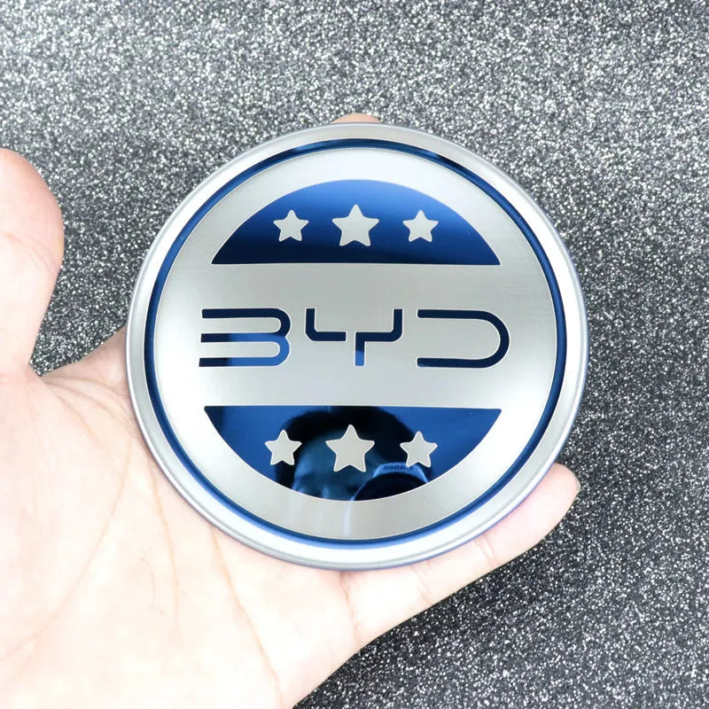 Emblème de volant BYD en inox, accessoire haut de gamme pour modèles électriques, main tenant le logo.