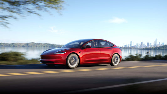 Tesla Model 3 rouge sur une route près d'un lac, avec une vue sur la ville en arrière-plan, mettant en évidence ses performances et son design novateur