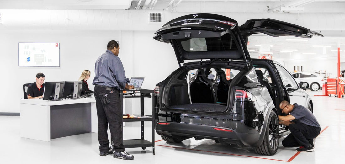 Rappel des Tesla Model 3 et Model Y en service, mécaniciens inspectant un véhicule dans un atelier.