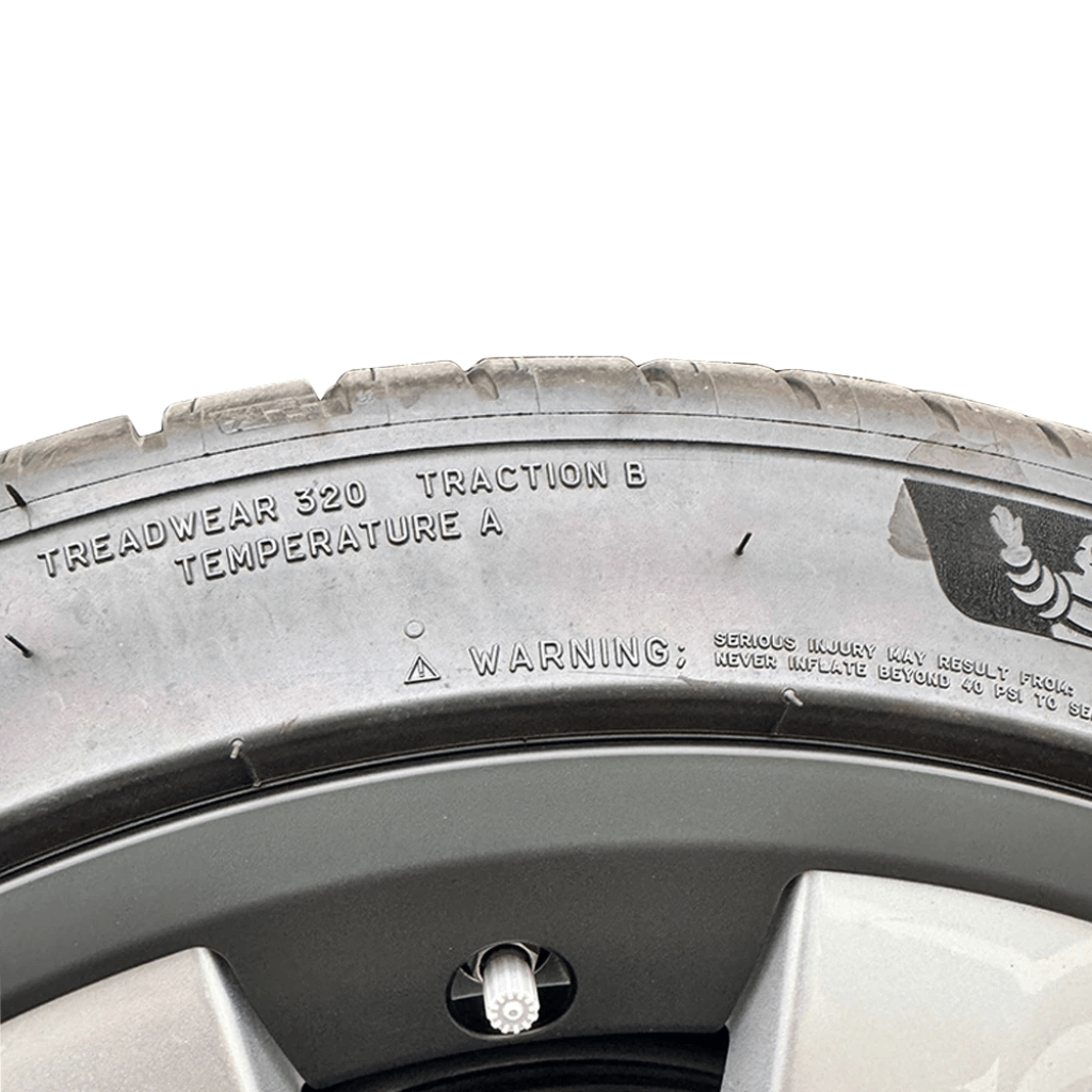 Close-up of car tire tread showing treadwear rating 320, traction B, and temperature A indicators.