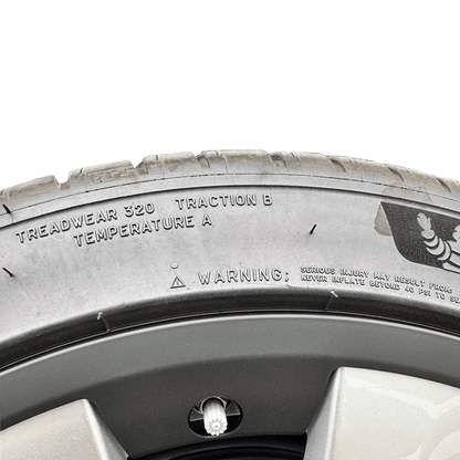Close-up of car tire tread showing treadwear rating 320, traction B, and temperature A indicators.