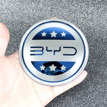 Emblème de volant BYD en inox, accessoire haut de gamme pour modèles électriques, main tenant le logo.